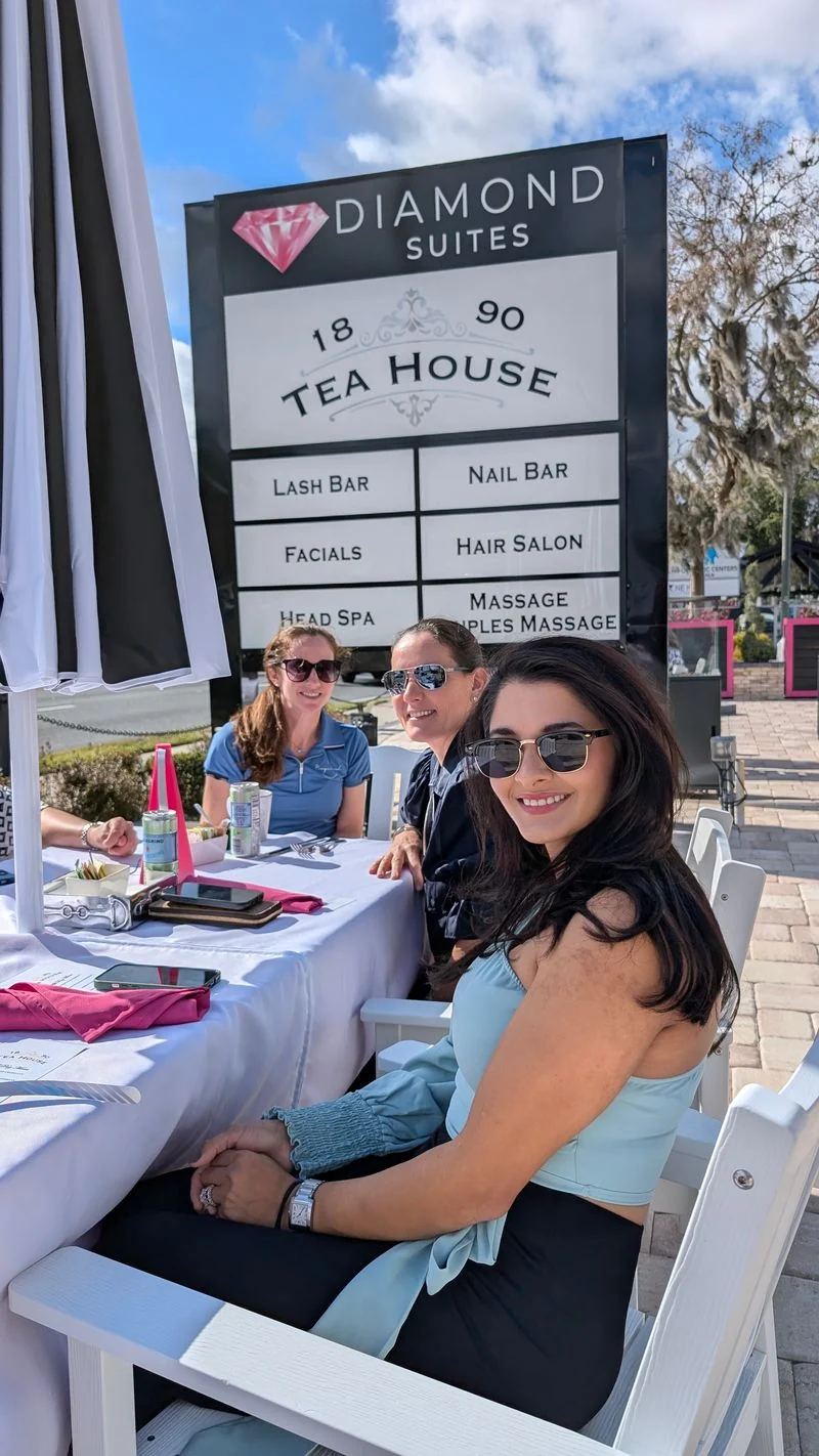 Guests enjoying an outdoor table beside the Diamond Suites sign
