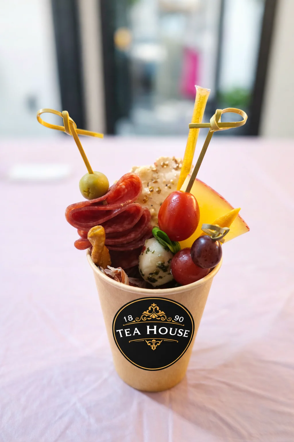 Individual charcuterie cup filled with meats, cheese, fruit, and crackers